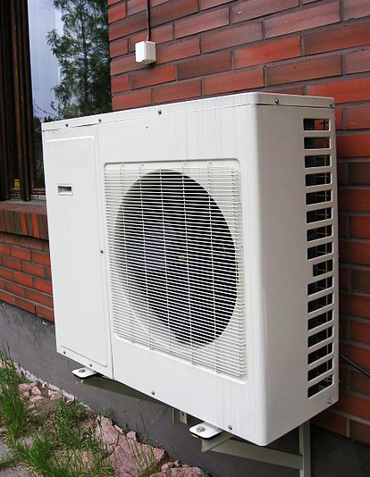 Air source heat pump outdoor unit mounted on a house wall